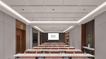 Un salón de conferencias con una larga mesa, sillas color naranja y una pantalla que muestra Hilton Garden Inn.
