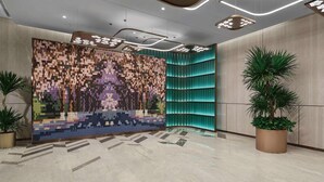 Un hall d’entrée moderne avec un mur orné de motifs, un éclairage encastré et un mur d’accent incurvé de couleur turquoise.