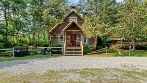 A rustic cabin with a wooden exterior, a red door, and a small porch.