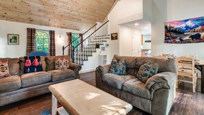 A spacious living room with two sofas, a wooden coffee table, and a staircase leading to an upper level.