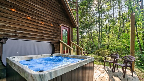 A hot tub on a wooden deck with a view of a forest.