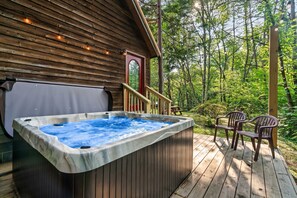 Un bain à remous sur une terrasse en bois, avec vue sur une forêt.