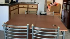 Una cucina compatta con tavolo e sedie, un forno a microonde e un lavello.
