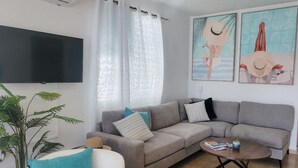 Un soggiorno moderno con un divano grigio, un tavolino da caffè e una TV a parete.