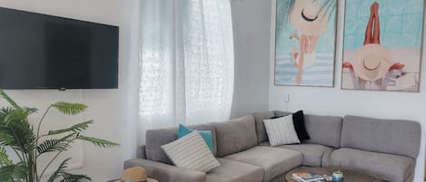 A modern living room with a grey sofa, a coffee table, and a TV mounted on the wall.