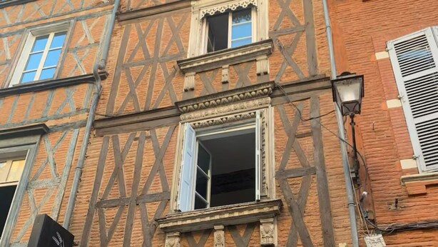 Un edificio con vigas de madera a la vista y un letrero que dice 'LANGERIE DES CARMES'.