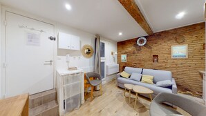 Una sala de estar moderna con una pared de acento de madera, un sofá gris y una pequeña zona de comedor.