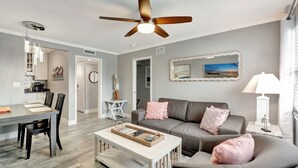 A modern living room with a gray sofa, a coffee table, and a ceiling fan. - Olde Naples beautiful Condo Steps to Pier, Beach, Sunsets and restaurants!  (Naples)