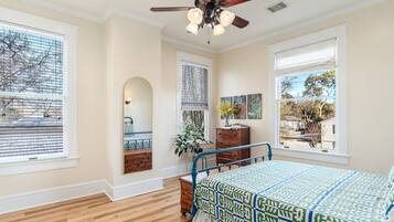 A bedroom with a bed, a dresser, a mirror, and a ceiling fan.