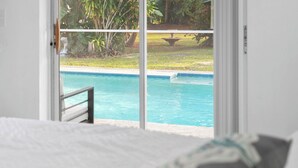 A bedroom with a view of a swimming pool through a glass door. - Family house  4 bedrooms 3 bath sleeps 12. 2 master suites Naples heated pool (Naples)