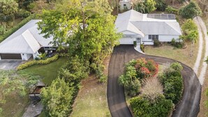 A residential area with two houses, a driveway, and surrounding greenery. - Family house  4 bedrooms 3 bath sleeps 12. 2 master suites Naples heated pool (Naples)
