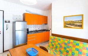 Compact kitchen with modern appliances, a gas stove, and a colorful bench.