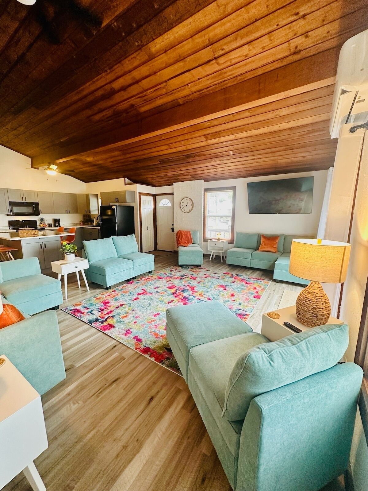Una sala de estar acogedora con sofás azul claros, una alfombra colorida y piso de madera.