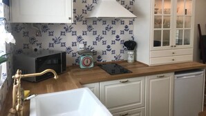 Una cocina con armarios blancos, encimera de madera, pileta blanca y un salpicadero con diseño.