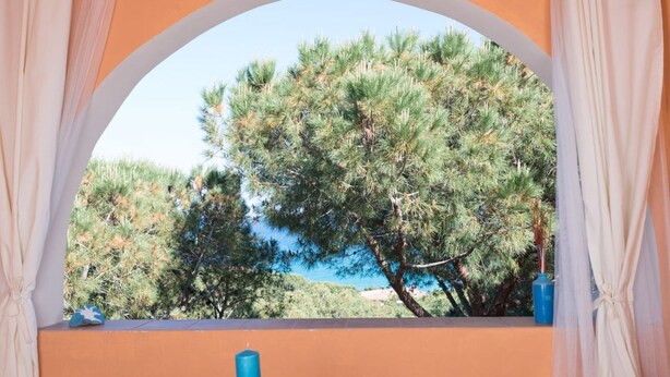A room with a view of pine trees and a body of water through an arched window. - [Dimora dell'Arco] Seaside Apartment with Stunning Views (Orosei)