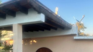 Una casa con porche cubierto, puerta de madera y antena parabólica.