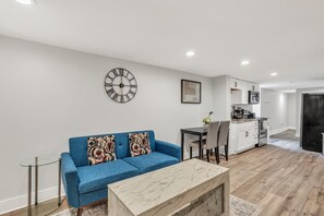 Una sala de estar moderna con un sofá azul, una mesa de centro de mármol y un reloj de pared.