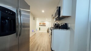 Une cuisine moderne dotée d’appareils électroménagers en acier inoxydable, de meubles blancs et d’un plancher en bois.