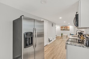 Una cocina moderna con electrodomésticos de acero inoxidable, encimera de mármol y suelo de madera.