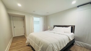 Une chambre à coucher avec un lit, un plancher en bois, une porte et une fenêtre.