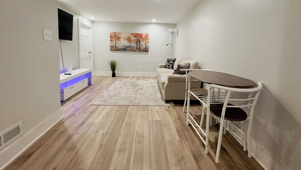 Un salon moderne doté d’un téléviseur à écran plat, d’un canapé, d’une table basse et d’un coin repas avec une chaise blanche.