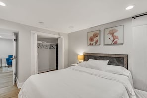 Une chambre à coucher avec un lit, une table de chevet, une lampe, une armoire et une chaise.