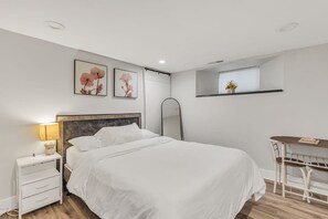 Une chambre à coucher moderne, comprenant un lit, une table de chevet, une lampe et un petit bureau avec une chaise.