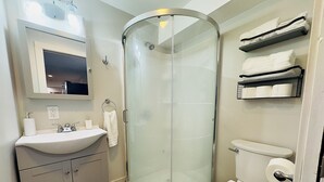 Une salle de bain moderne avec une douche à parois de verre, un lavabo blanc, des toilettes et un miroir au-dessus du lavabo.