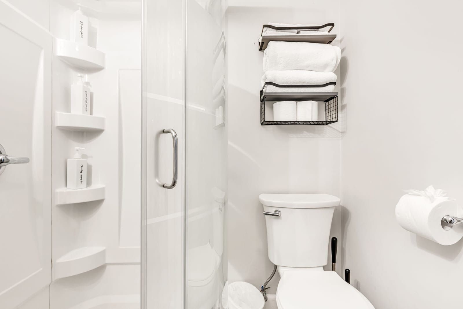 A modern bathroom with a glass shower enclosure, a toilet, and a towel rack.
