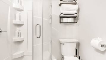 A modern bathroom with a glass shower enclosure, a toilet, and a towel rack.