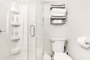 A modern bathroom with a glass shower enclosure, a toilet, and a towel rack. - Experience comfort and convenience in our newly renovated basement retreat. (Indianapolis)
