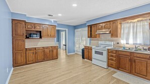 Una cocina amplia con armarios de madera, un microondas, una estufa y un fregadero.