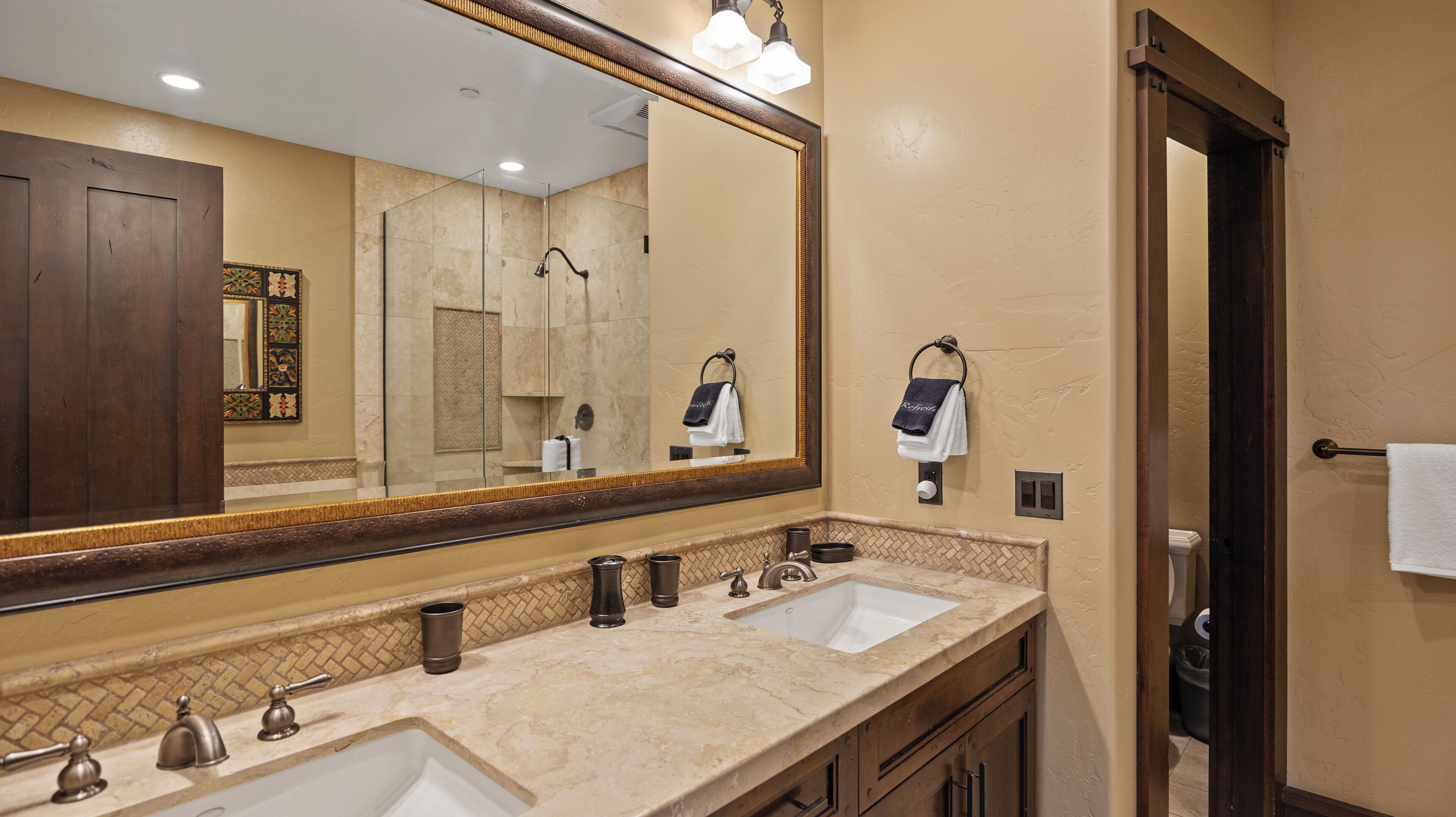A bathroom with two sinks, a large mirror, and a towel rack.