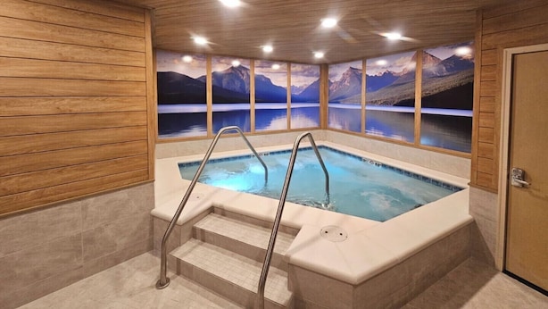A hot tub with a view of mountains through large windows. - Cozy condo, next to the ski slopes with 2 private balconies (Whitefish)
