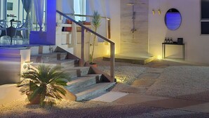 Een modern huis met een trap naar een balkon, een zwembadgedeelte en een goed verlichte entree.