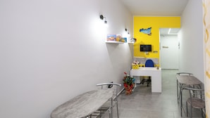 A modern office space with a desk, chairs, a computer, and a shelf with books and decorative items. - Splendori Rooms (Palermo)