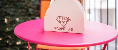 A pink table with a Splendorii branded paper bag on top.