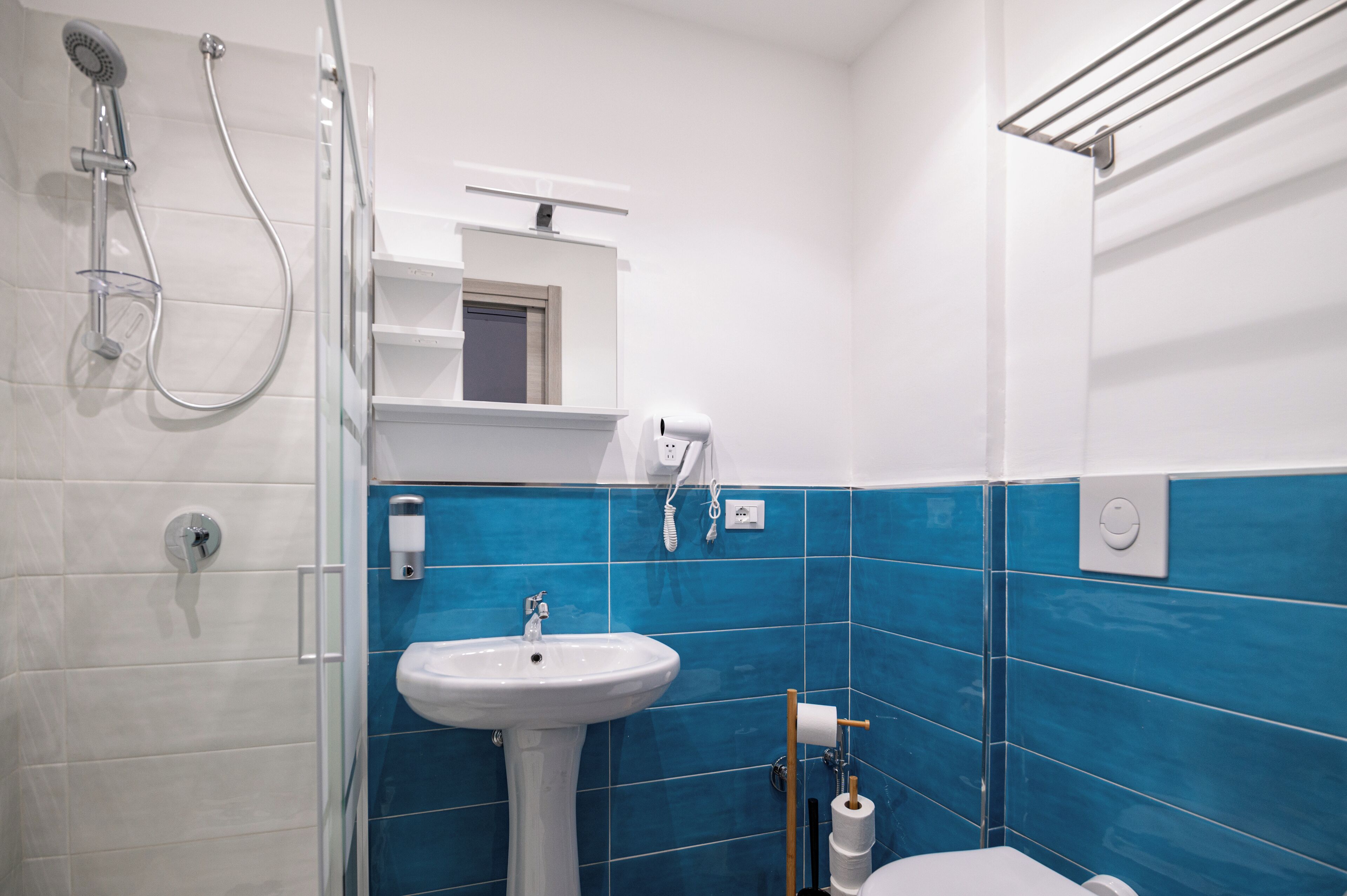 Une salle de bain avec un lavabo blanc, une douche et des murs recouverts de carreaux bleus.