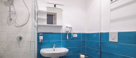 Un baño con lavamanos blanco, ducha y paredes con azulejos azules.