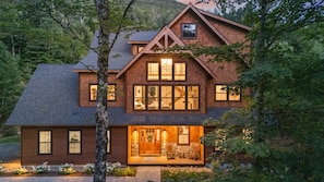Une maison en bois à deux étages, dotée d’un porche avant bien visible et de grandes fenêtres.