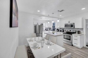 Enjoy a formal dining experience in this stylish kitchen with a central island, sleek cabinetry, and pendant lighting.
