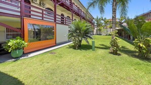A hotel with a covered outdoor area, a well-maintained lawn, and several palm trees. - AP 08A Ala Morrinhos Residencial Solavir (Bombinhas)