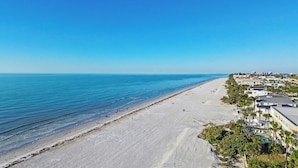 Ein Strand mit freiem Blick auf das Meer und einer Reihe von Häusern mit Pool.