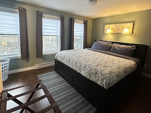 Relax in a spacious bedroom with a large bed, dark headboard, and wall-mounted lamp.