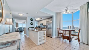 A modern kitchen with a central island, white cabinetry, stainless steel appliances, and a large window offering a city view.