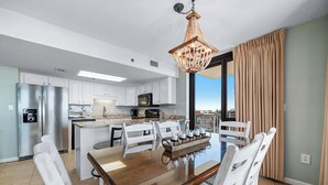 Een moderne keuken met witte kasten, roestvrijstalen apparatuur en een groot eiland met zitplaatsen.