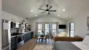 A modern kitchen with a dining area, a bedroom with a bed, and a ceiling fan. - Bright and Modern Studio Guesthouse - near RiNo! (Denver)