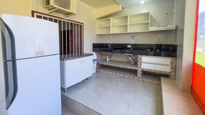A compact kitchen with a refrigerator, a sink, and a tiled backsplash. - AP 08B Ala Morrinhos Residencial Solavir (Bombinhas)