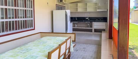 A small, compact room with a bed, a kitchenette, and a window with bars.