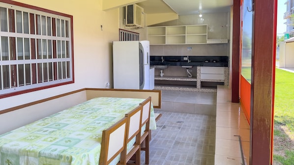 A small, compact room with a bed, a kitchenette, and a window with bars.